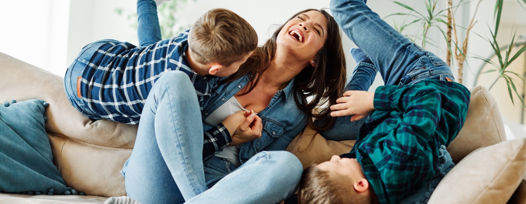 a family laughing and playing on a sofa